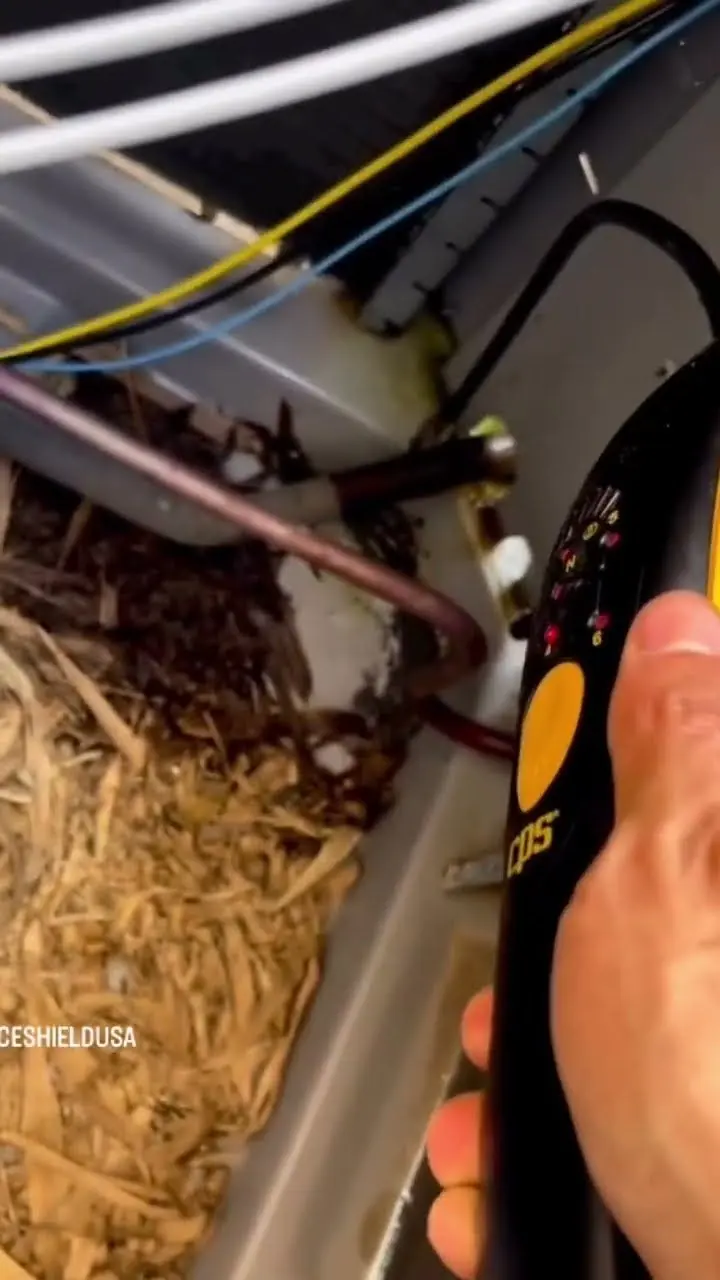 Video thumbnail showing an electronic refrigerant leak detector held next to copper tubing inside an outdoor unit packed with leaf debris