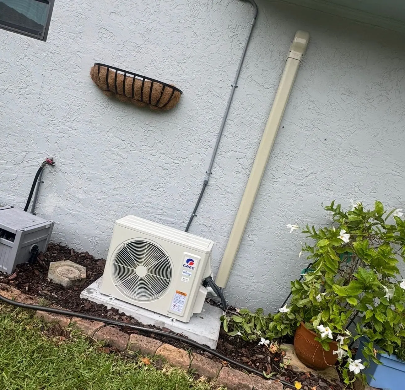 Ductless mini-split outdoor unit installed on a pad beside a stucco home
