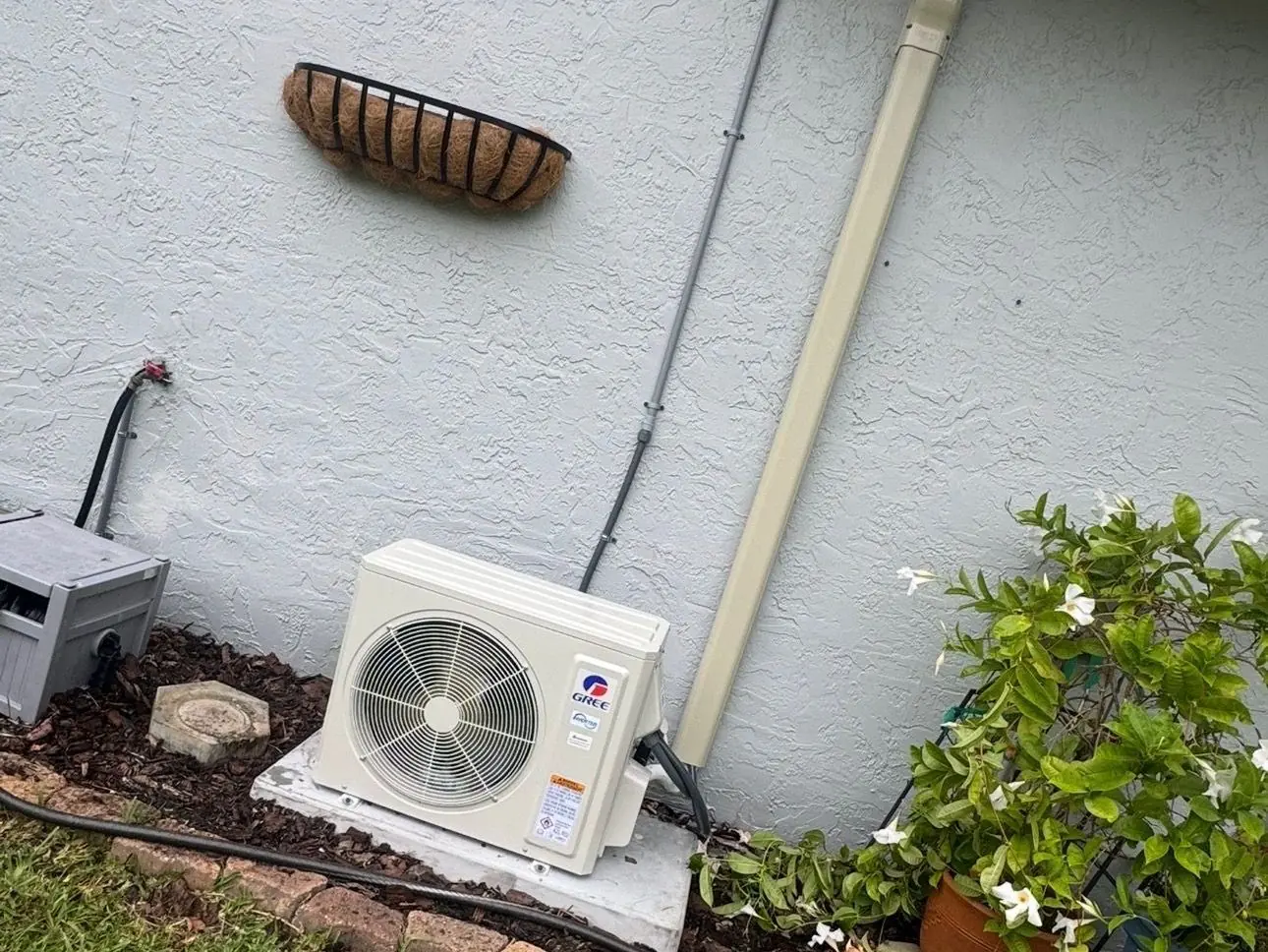Ductless mini-split outdoor unit installed on a pad beside a stucco home