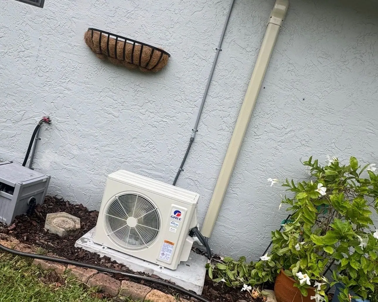 Ductless mini-split outdoor unit installed on a pad beside a stucco home