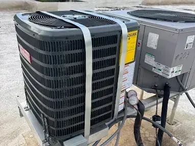 Rooftop condensing units on their stands, secured with hurricane straps