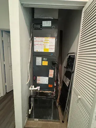 New air handler installed in a hallway closet with louvered doors