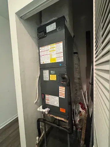 New air handler in a closet, with its refrigerant and drain connections at the base