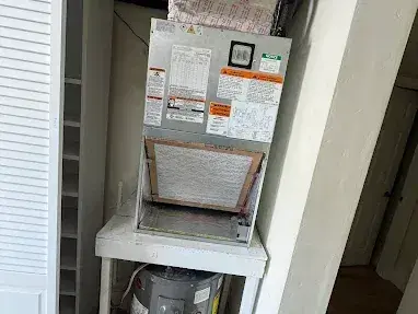 Air handler on a stand in a closet above the water heater, with the return filter in place