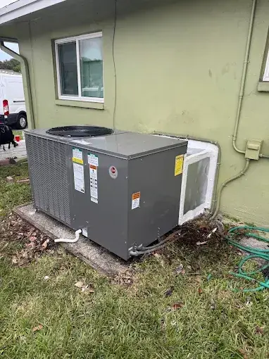 New packaged air conditioning unit on a pad beside a house