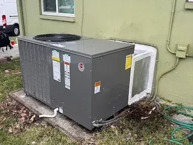 New packaged air conditioning unit on a pad beside a house