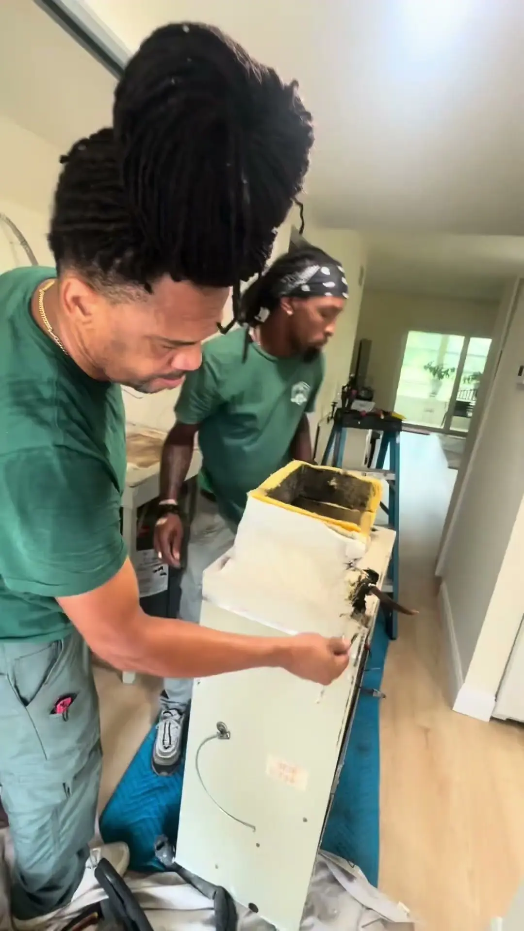 Video thumbnail showing two technicians inspecting a removed indoor air-handler cabinet with dark staining at one corner