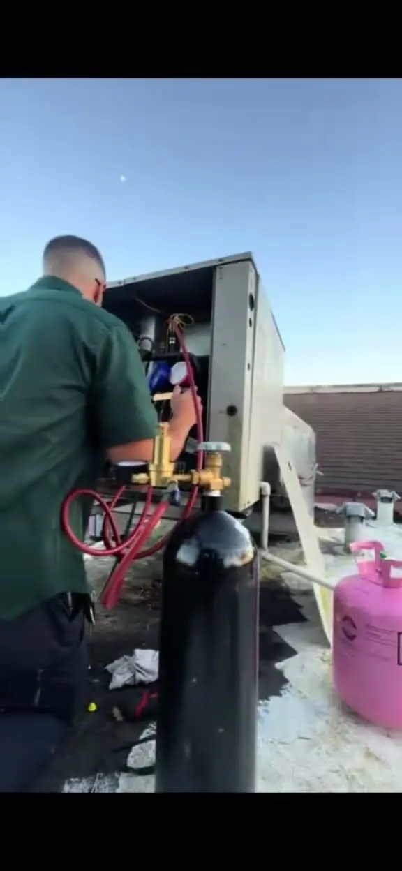 Video thumbnail showing a technician working on a rooftop AC unit at dusk, with refrigerant gauges and cylinders beside it