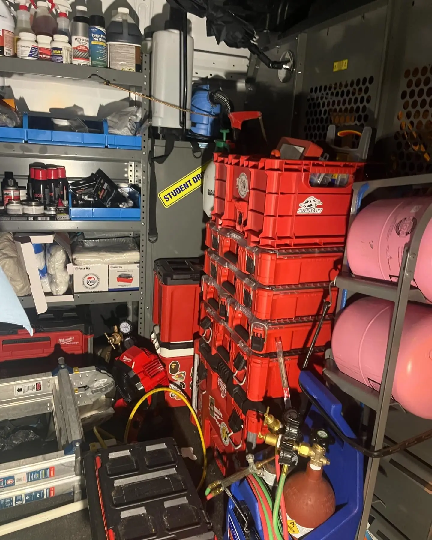 Inside a service van stocked with parts bins, stacked tool cases and refrigerant cylinders