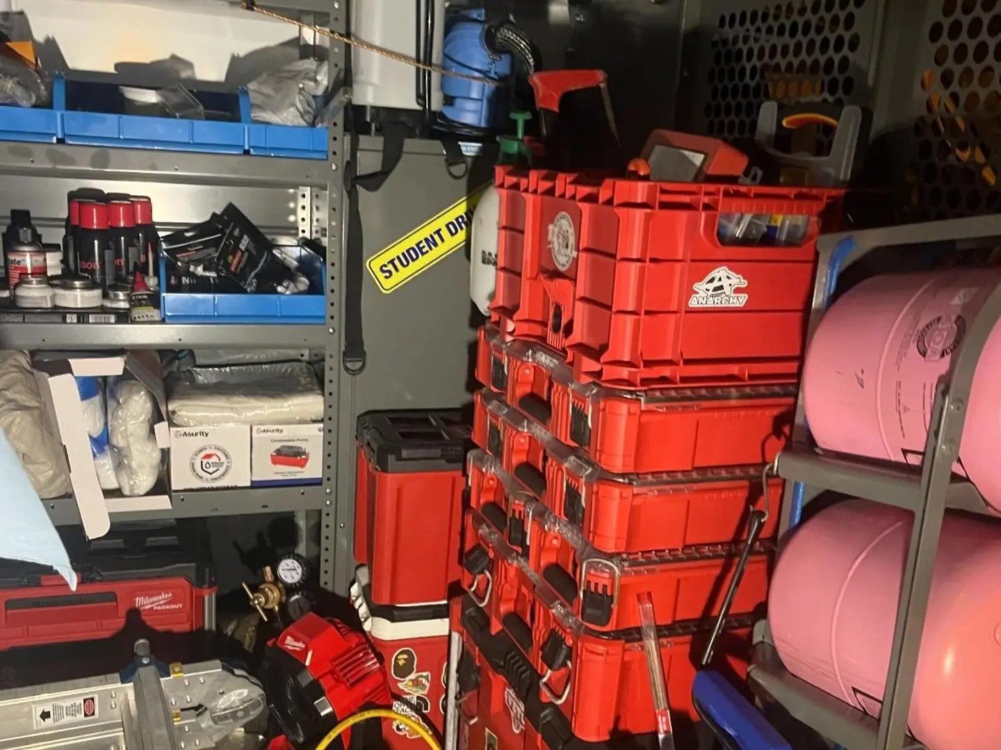 Inside a service van stocked with parts bins, stacked tool cases and refrigerant cylinders