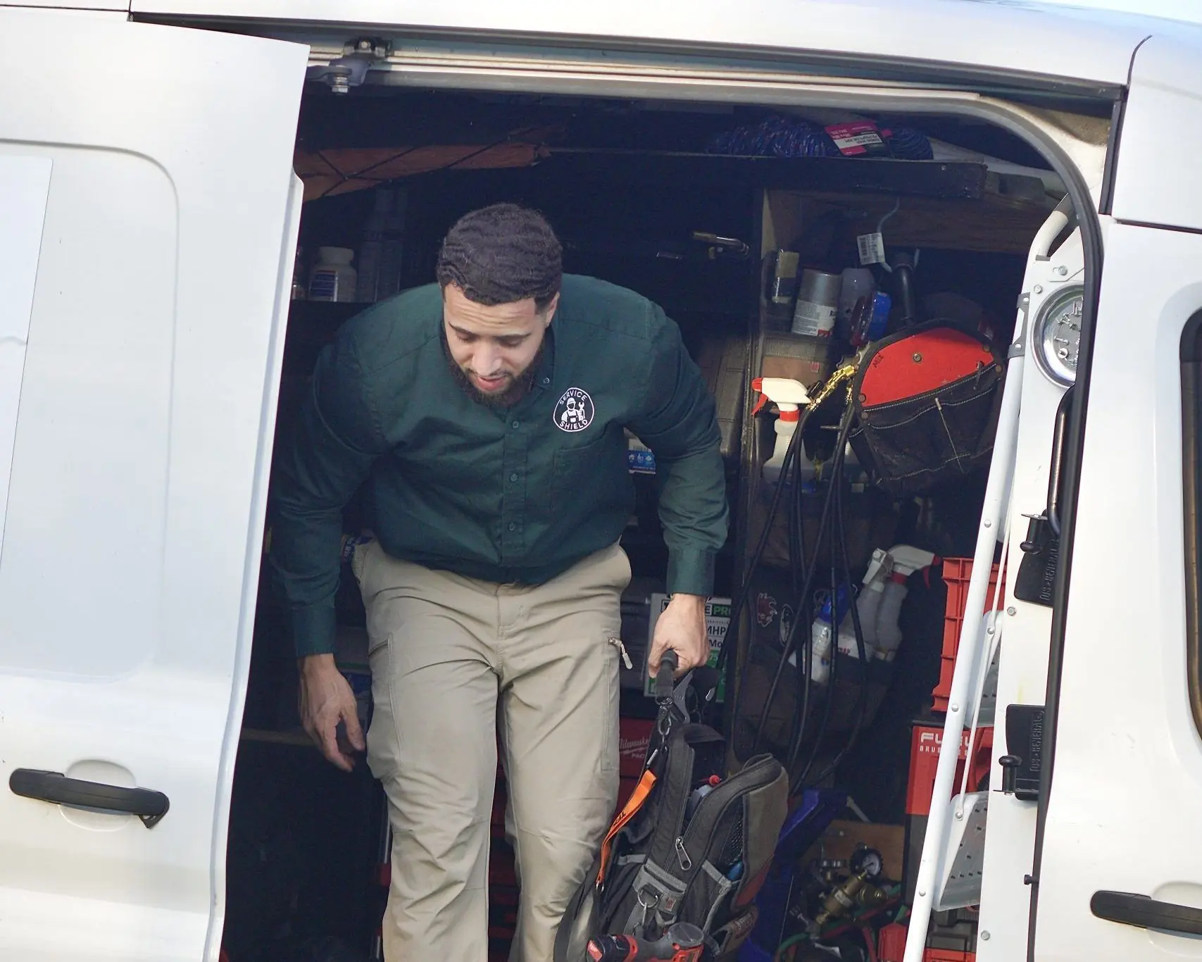 Service Shield technician stepping out of a service van stocked with tools and parts