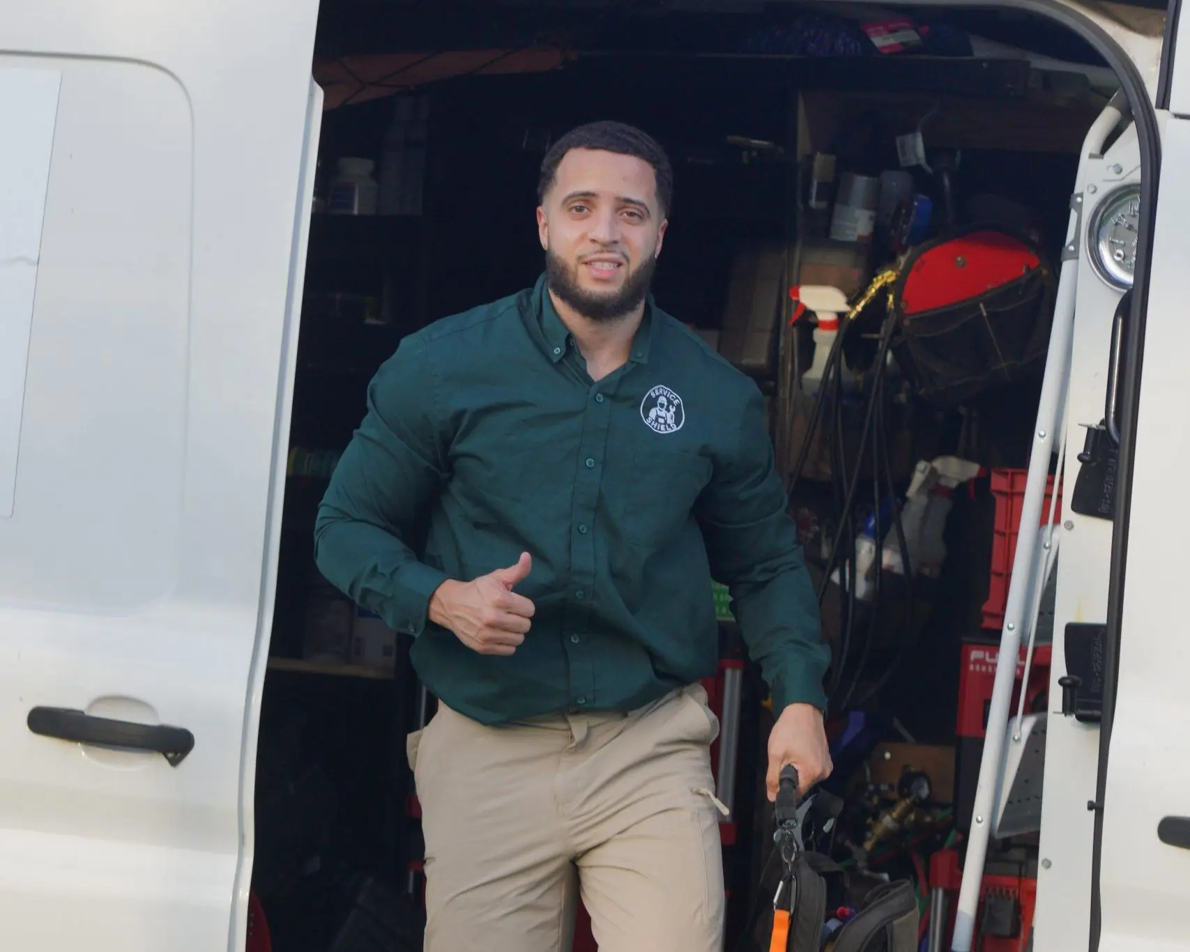 Service Shield technician stepping down from the service van with a tool bag