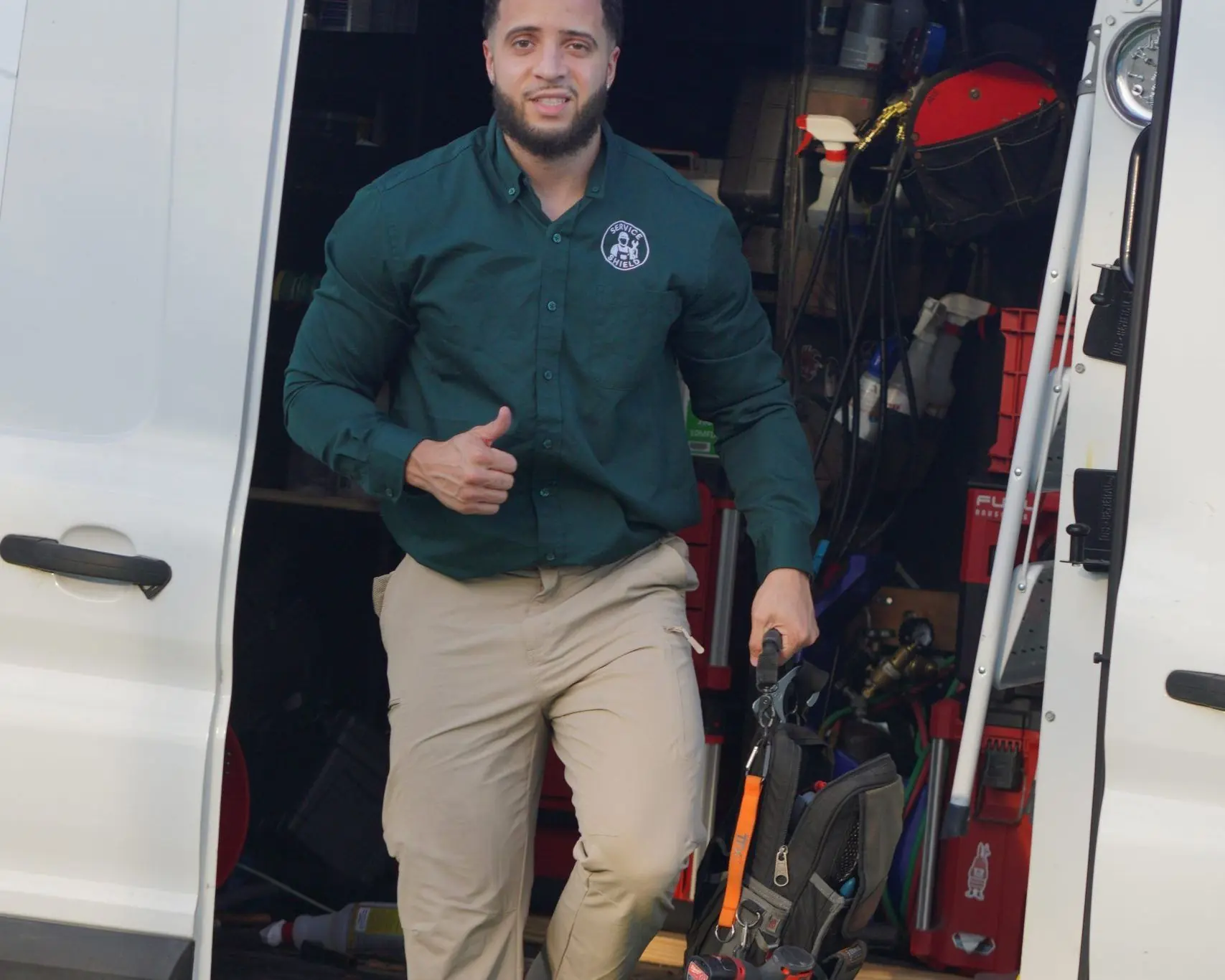 Service Shield technician climbing out of the service van with tools in hand