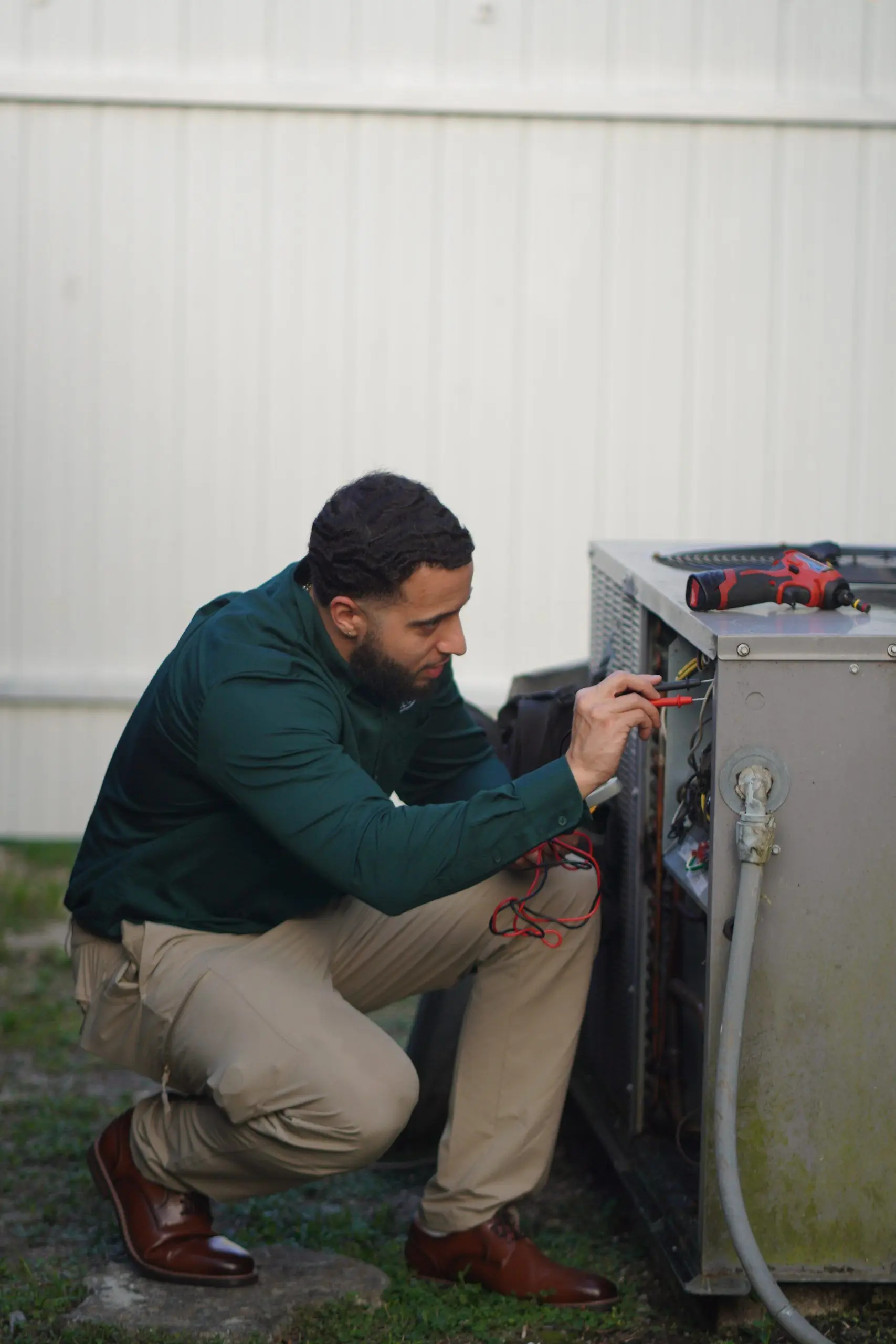 Service Shield technician testing the wiring in an outdoor unit's electrical panel