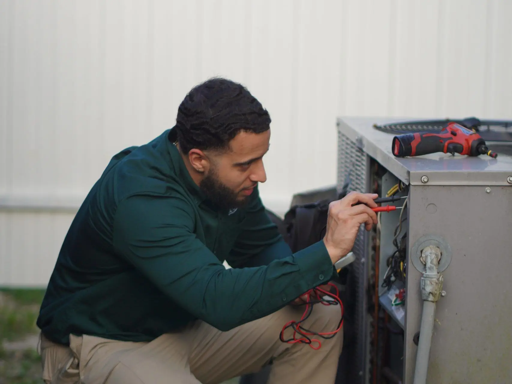 Service Shield technician testing the wiring in an outdoor unit's electrical panel