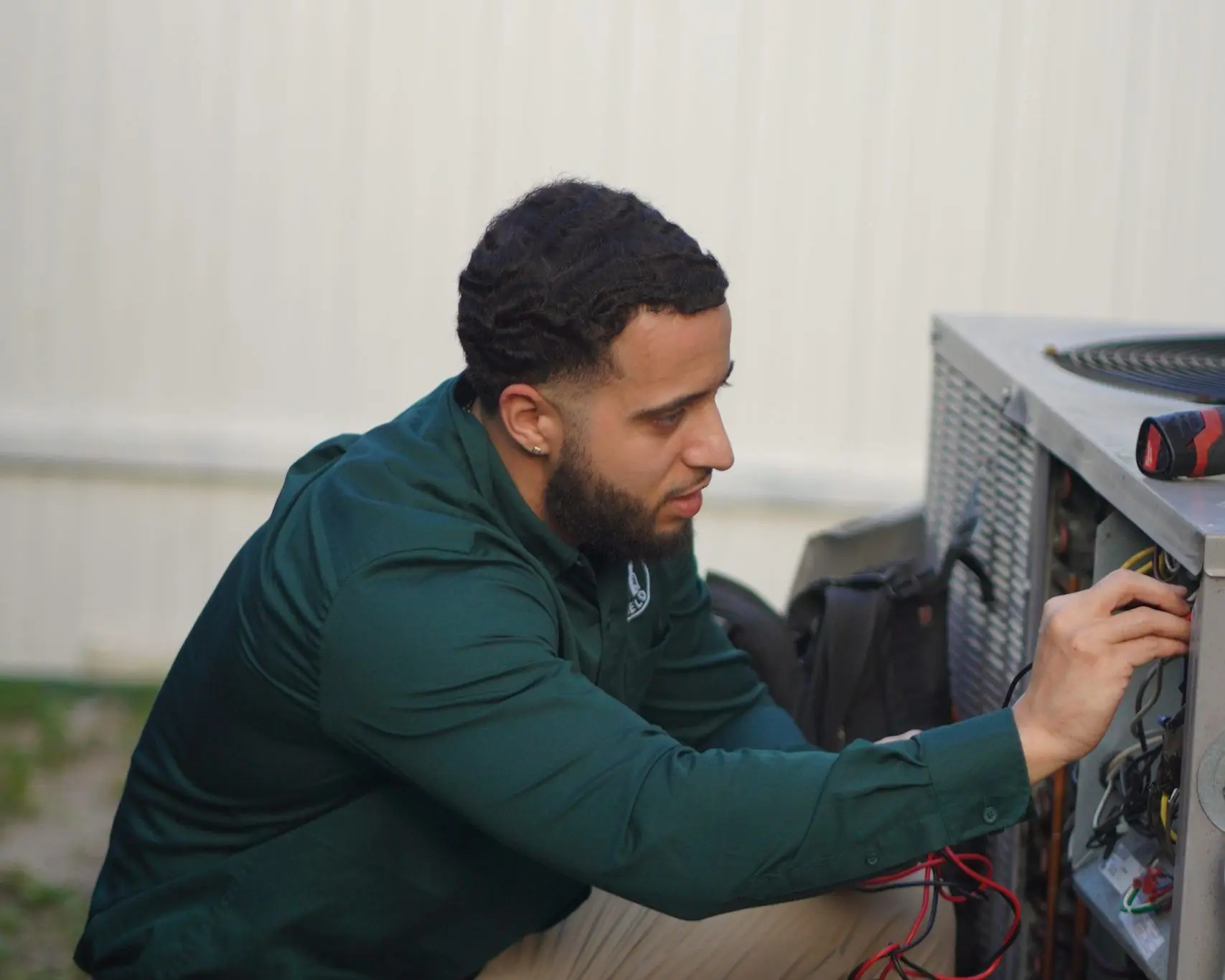 Service Shield technician checking electrical components inside an outdoor unit