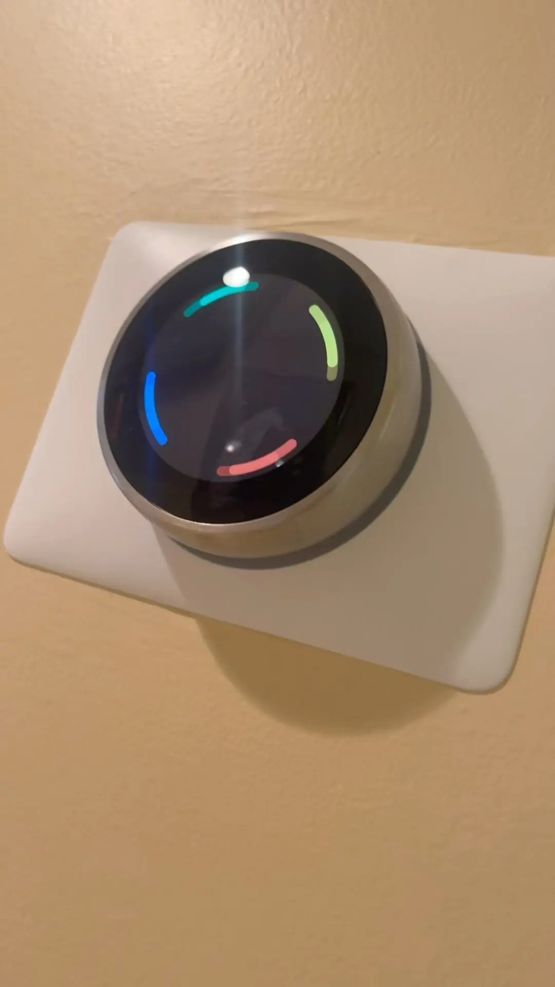 Round smart thermostat with a lit display mounted on an interior wall