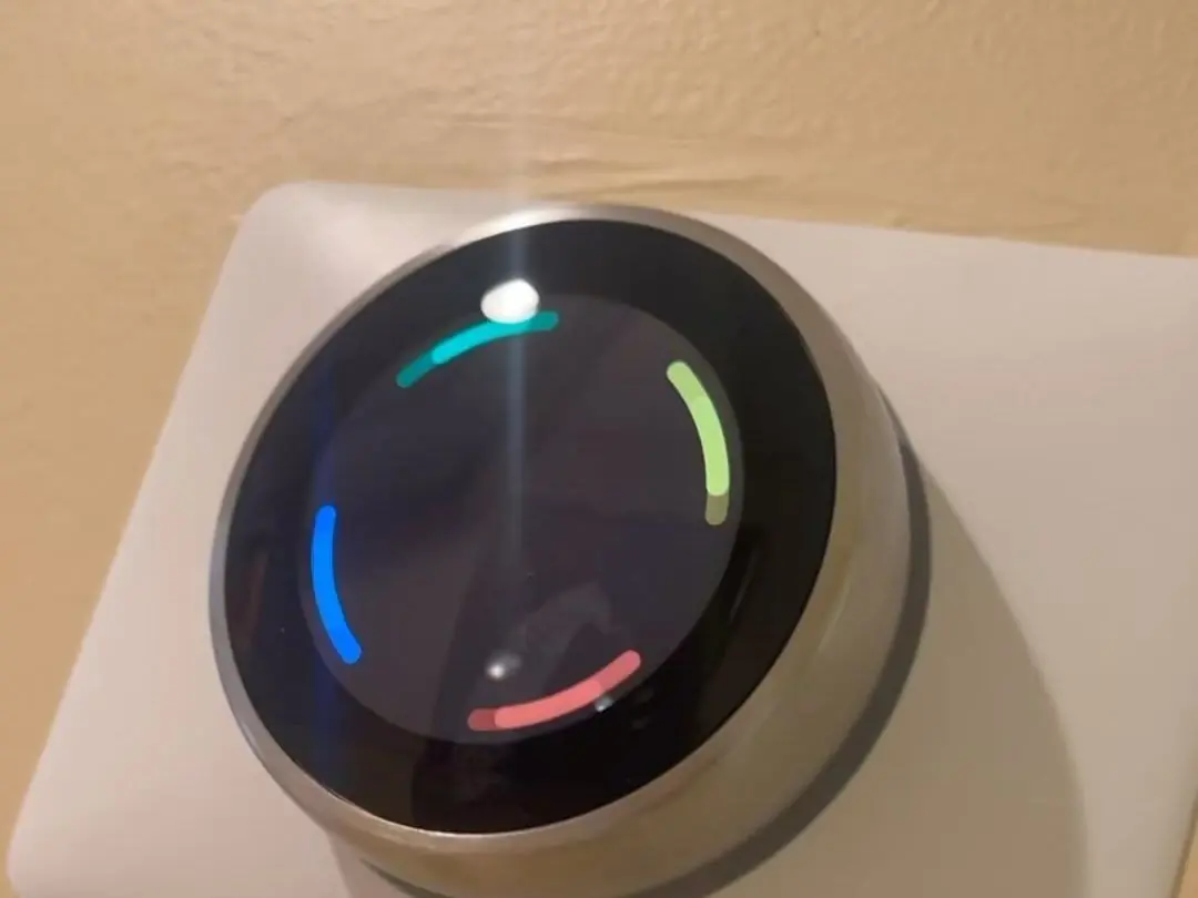 Round smart thermostat with a lit display mounted on an interior wall