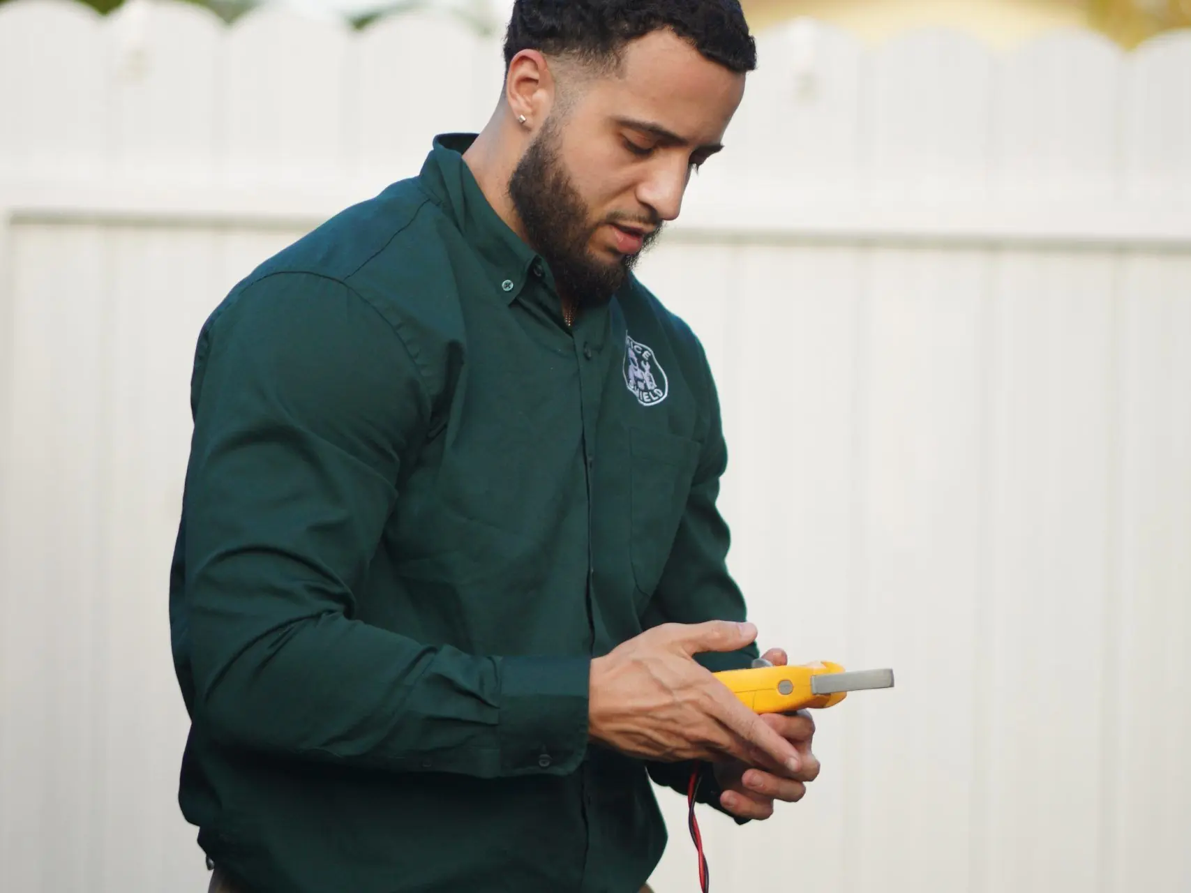 Technician standing in a backyard reading a digital multimeter with its test leads connected